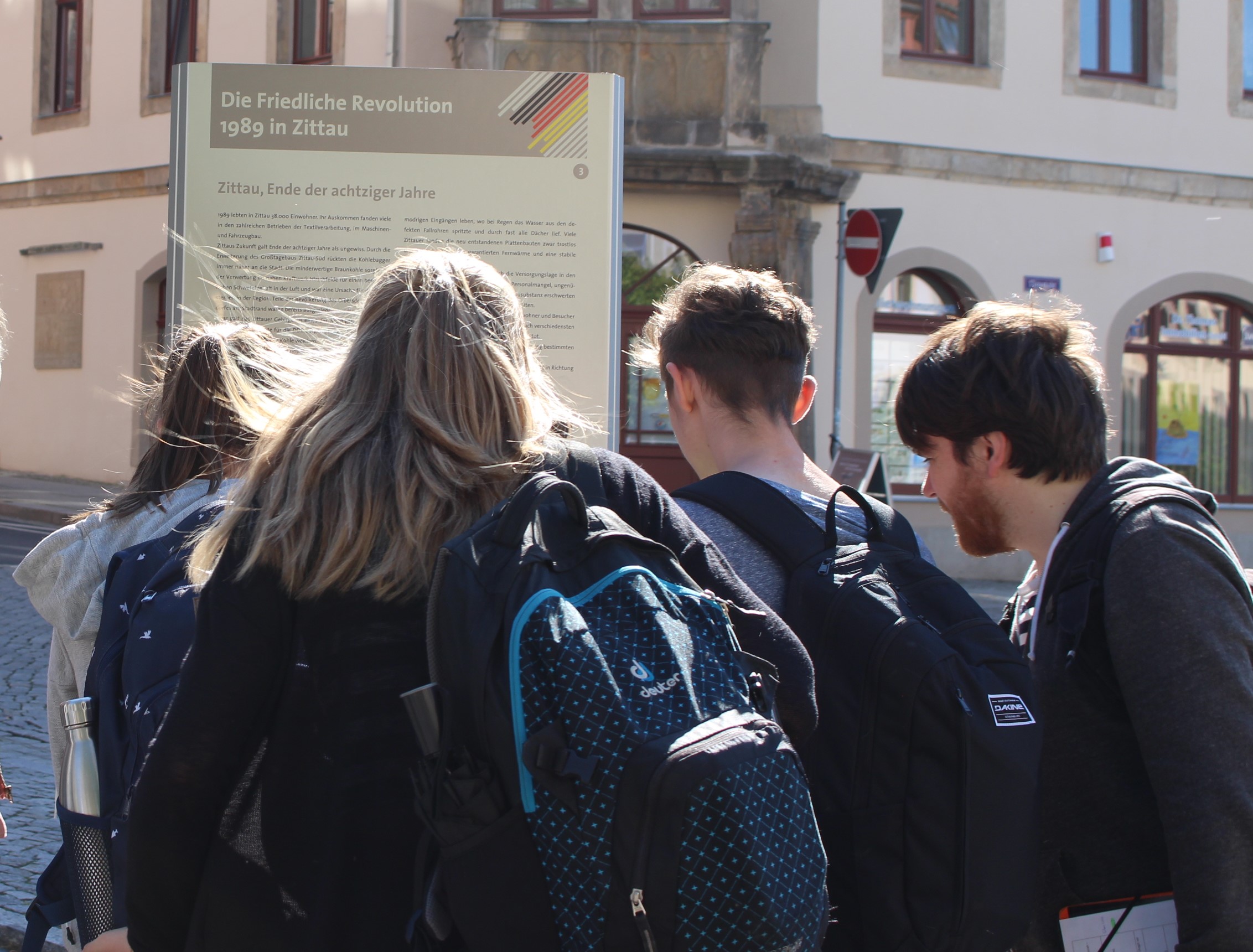 Das Bild zeigt eine Gruppe, die eine der Erinnerungsstelen in der Zittaur Innenstadt anschaut.