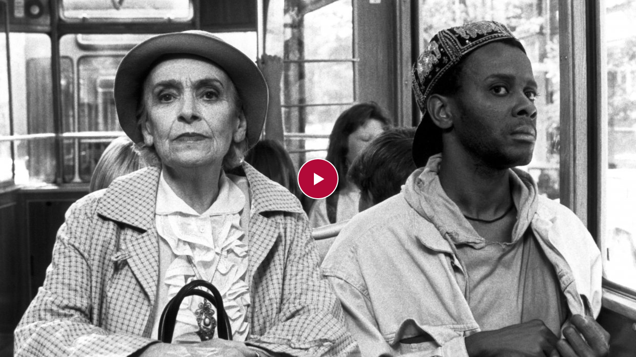 Das Bild zeigt eine ältere Dame, die neben einer Person of Colour in der Straßenbahn sitzt.